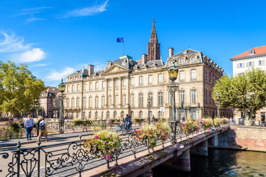 Main facade of the Rohan palace facing the river Ill and Sainte-Madeleine bridge with the steeple of Notre-Dame cathedral in Strasbourg, France.