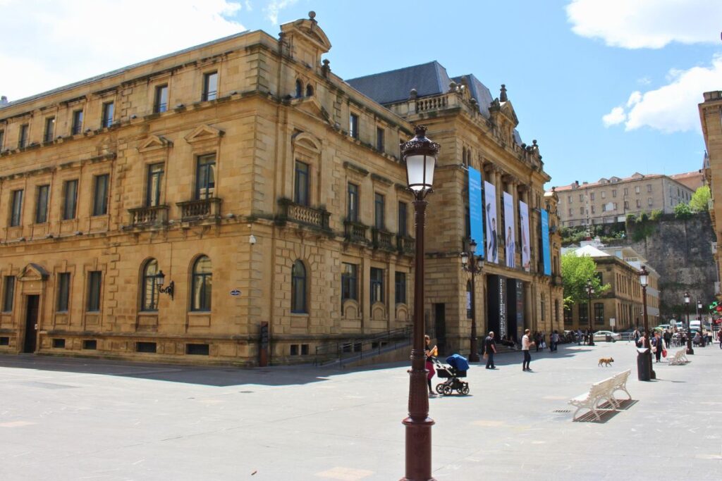 Die neoklassizistische Sandsteinfassade des Kulturzentrums und der Bibliothek Koldo Mitxelena in San Sebastián an einem sonnigen Tag auf einem großen Platz.