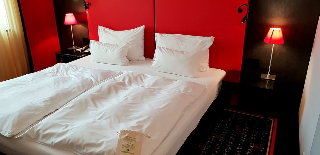 vienna-house-easy-pilsen-hoteltipp-tsjechisch-titel-kamer-bed "class =" wp-image-9864 "srcset =" https://www.nicolos-reiseblog.de/wp-content/uploads/2019/ 02 / vienna-house-easy-pilsen-hoteltipp-tsjechisch-titel-kamer-bed-1024x498.jpg 1024w, https://www.nicolos-reiseblog.de/wp-content/uploads/2019/02/vienna-house -easy-pilsen-hoteltipp-tsjechisch-titel-kamer-bed-300x146.jpg 300w, https://www.nicolos-reiseblog.de/wp-content/uploads/2019/02/vienna-house-easy-pilsen- hoteltipp-tsjechisch-titel-kamer-bed-800x389.jpg 800w, https://www.nicolos-reiseblog.de/wp-content/uploads/2019/02/vienna-house-easy-pilsen-hoteltipp-tschechien-titel -zimmer-bett.jpg 1080w, https://www.nicolos-reiseblog.de/wp-content/uploads/2019/02/vienna-house-easy-pilsen-hoteltipp-tschechien-titel-zimmer-bett-300x146@ 2x.jpg 600w "sizes =" (max-width: 1024px) 100vw, 1024px "/></figure>
<p>Het hotel heeft kleine voorzieningen voor de gasten. Dus ik geniet er erg van, als ik na mijn aankomst eerst koffie of thee in de kamer kan bereiden. In het Vienna House Easy Pilsen is er een kleine selectie die niets te wensen overlaat – het warme water dat ik zelf in de ketel maak.</p>
<figure class=