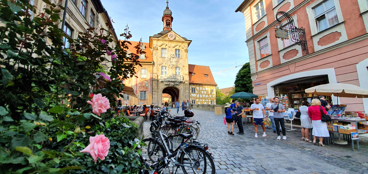 Wat-je-moet-zien-Bamberg-oud-herenhuis-poort "width =" 1200 "height =" 569 "data-wp-pid =" 11136 "srcset =" https://www.nicolos-reiseblog.de/ wp-content / uploads / 2019/08 / What-must-see-one-Bamberg-old-townhouse-tor.jpg 1200w, https://www.nicolos-reiseblog.de/wp-content/uploads/2019/08 /What-must-man-see-Bamberg-altes-rathaus-tor-300x142.jpg 300w, https://www.nicolos-reiseblog.de/wp-content/uploads/2019/08/Was-muss-man- see-bamberg-old-town-gate-tor-1024x486.jpg 1024w, https://www.nicolos-reiseblog.de/wp-content/uploads/2019/08/Was-muss-man-sehen-Bamberg-altes-rathaus -tor-50x24.jpg 50w, https://www.nicolos-reiseblog.de/wp-content/uploads/2019/08/Was-muss-man-sehen-Bamberg-altes-rathaus-tor-800x379.jpg 800w "sizes =" (max-breedte: 1200px) 100vw, 1200px "/></p>
<hr/>
<h2>Nieuwe residentie met rozentuin</h2>
<p>Op een steenworp afstand van de Duomo ligt de nieuwe residentie, gebouwd in barok- en renaissancestijl. In de 17e eeuw was het de residentie van de prins-bisschoppen van Bamberg en in de 19e eeuw diende het als een koninklijke residentie.</p>
<p>Tegenwoordig huisvest de nieuwe residentie de Staatsbibliotheek, de Staatsgalerij en heeft 40 showrooms. Hier kijk ik naar en ben opgewonden, omdat de ene kamer mooier is dan de andere. Prachtige fresco's, schilderijen en vele antieke meubels uit de 17e en 18e eeuw doen me duiken in het pompeuze verleden. Vooral de keizerlijke hal met zijn rijke decoraties en de imposante kroonluchter zal me zeker nog lang bijblijven.</p>
<p>Na een bezoek aan de nieuwe residentie neem ik een pauze in de prachtige rozentuin op de binnenplaats. Als je fan bent van strakke lijnen, kom je hier op jouw kosten, omdat alle oppervlakken en rondels symmetrisch zijn gerangschikt. Ik loop door de rozentuin, langs verschillende stenen sculpturen en geniet van het ongelooflijke uitzicht op de oude stad.</p>
<p><span style=