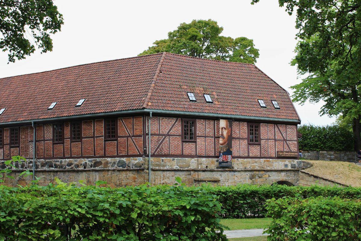 Das historische Backstein- und Fachwerkgebäude des norwegischen Widerstandsmuseums (Norges Hjemmefrontmuseum) auf dem Gelände der Festung Akershus, umgeben von grünen Bäumen.