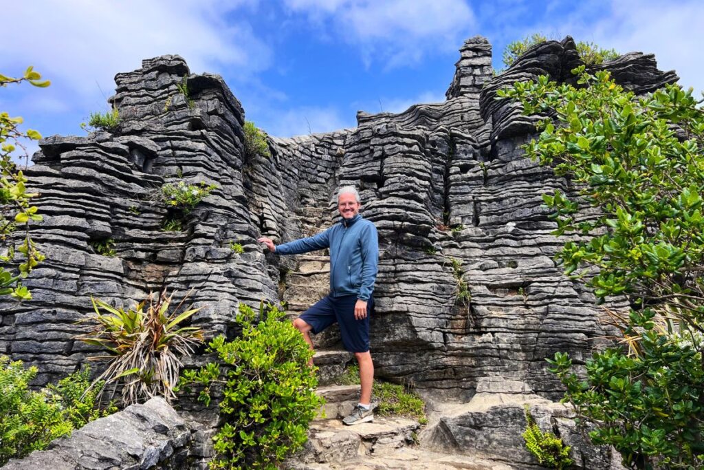 Nicolo Martin steht inmitten der bizarren, geschichteten Kalksteinformationen der Pancake Rocks bei Punakaiki an der wilden Westküste.