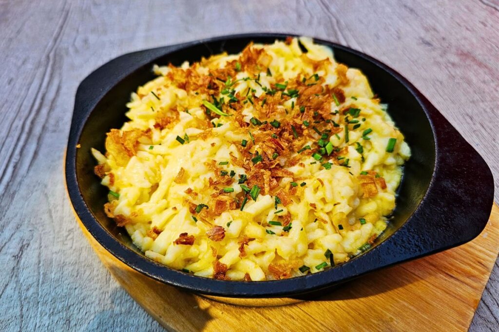 Traditionelle badische Käsespätzle mit Röstzwiebeln und Schnittlauch in Karlsruhe serviert