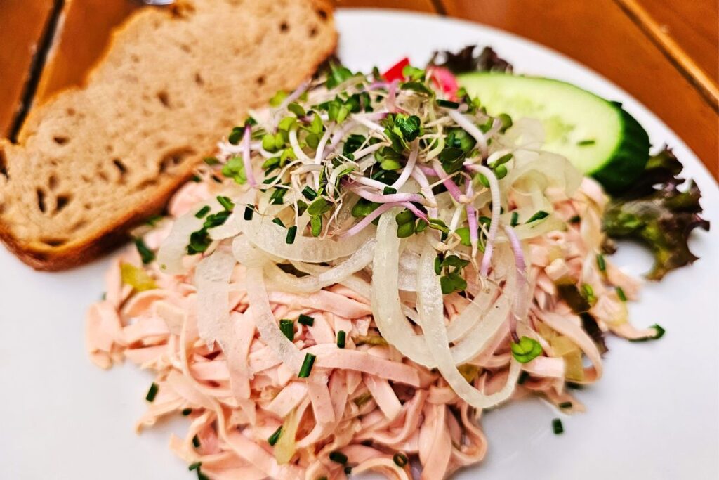 Badischer Wurstsalat mit Zwiebeln, Kräutern und Bauernbrot in Karlsruhe serviert