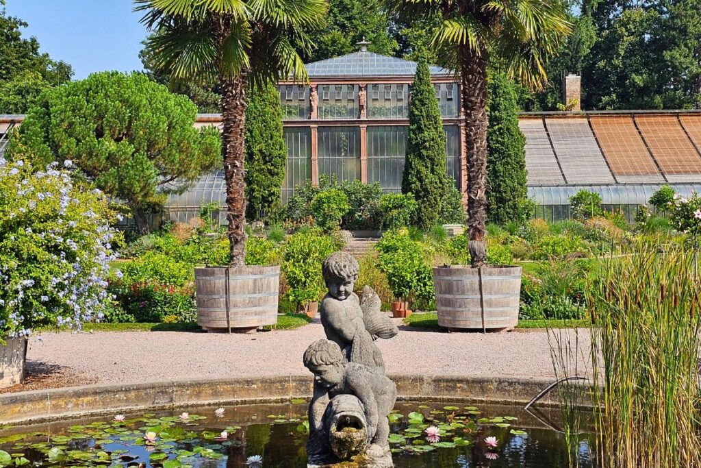 Historisches Gewächshaus im Botanischen Garten Karlsruhe mit Brunnenfigur und Seerosen