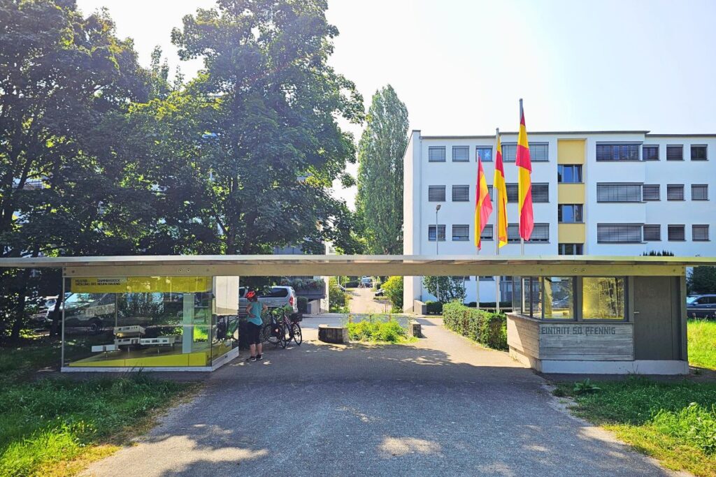 Eingang zur Dammerstock-Siedlung Karlsruhe mit Infopavillon und Fahnen