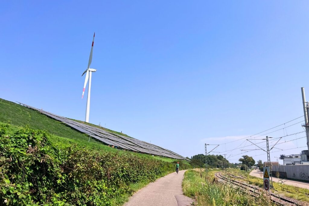 Radfahrer auf der NaturRADtour Karlsruhe am Rheinhafen mit Windrad, Solaranlage und Industrieanlagen