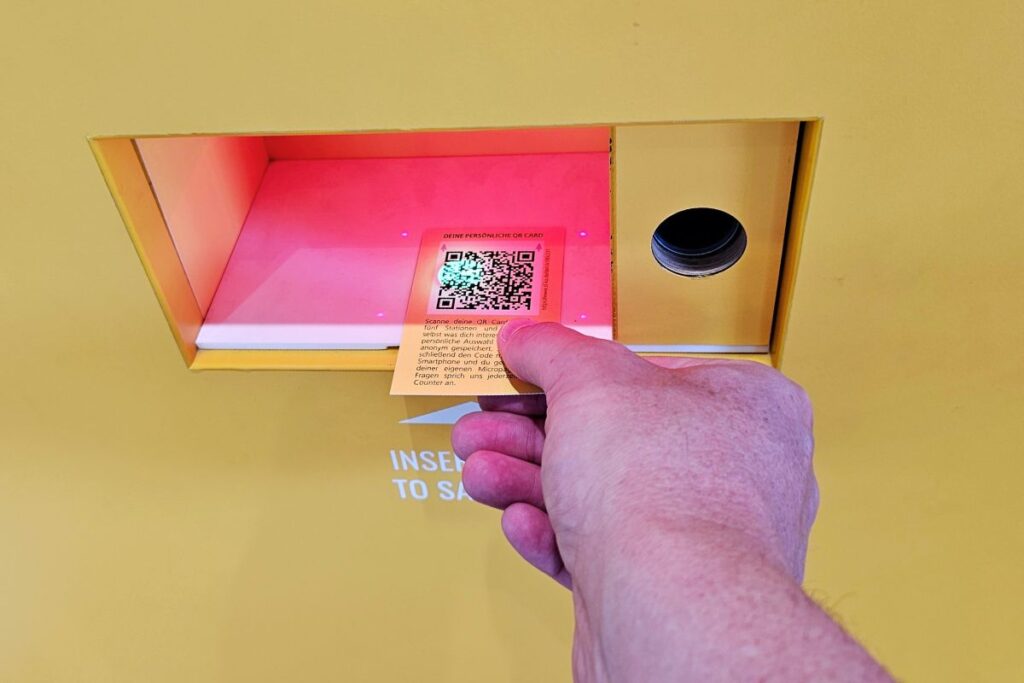 Besucher (Nicolo Martin) scannt eine QR-Card am Terminal im Schaufenster Karlsruhe