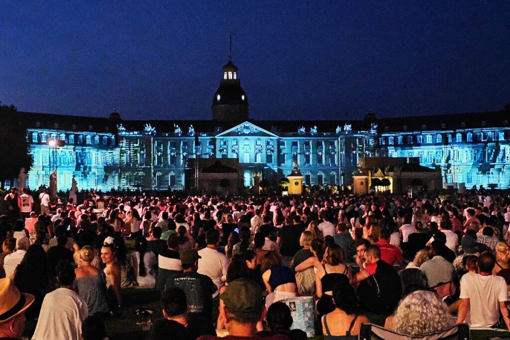 Menschenmenge beim nächtlichen Besuch der Schlosslichtspiele Karlsruhe vor dem erleuchteten Schloss