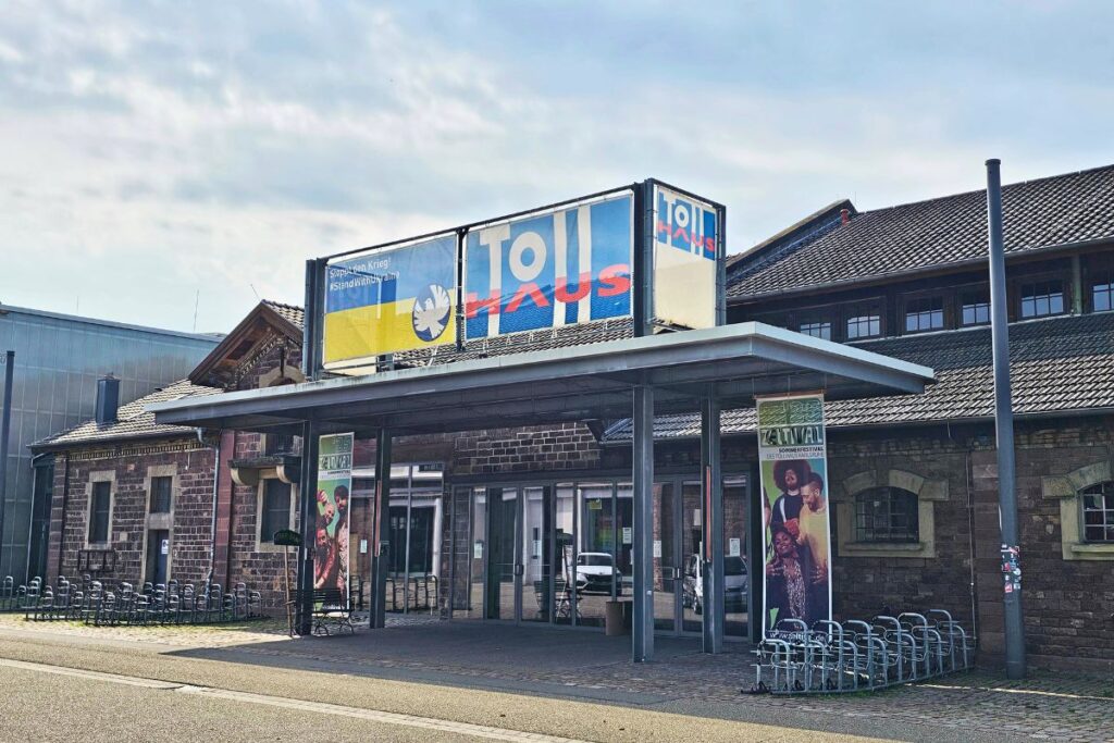 Eingang zum Tollhaus im Alten Schlachthof Karlsruhe mit Banner und Glasfront