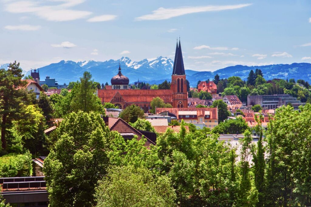 Blick auf Bregenz mit Kirche und Alpenpanorama im Hintergrund