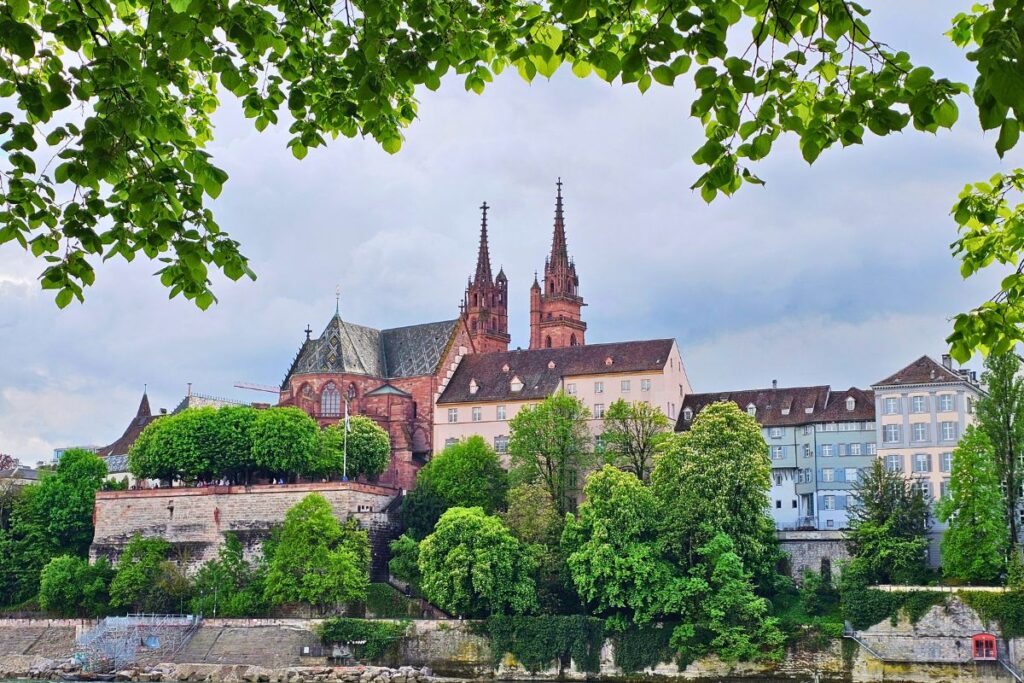 Basler Münster über dem Rhein mit Altstadthäusern und grünen Bäumen