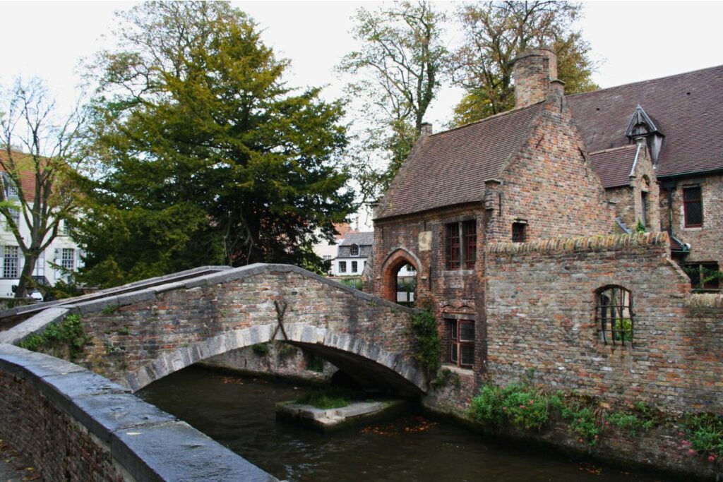 Historische Steinbrücke über einen Kanal in Brügge, umgeben von Backsteinhäusern