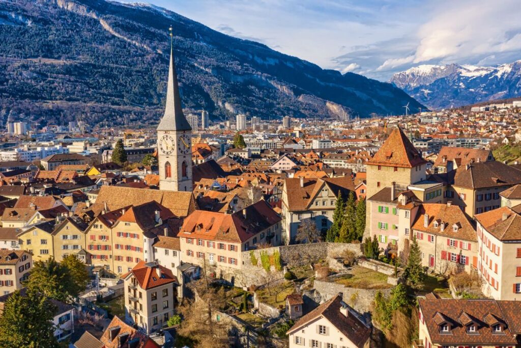 Blick über die Altstadt von Chur mit Kirchturm und Alpen im Hintergrund