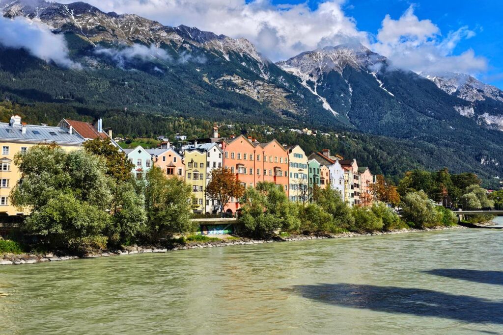 Bunte Häuserzeile entlang des Inn mit Alpenkulisse in Innsbruck