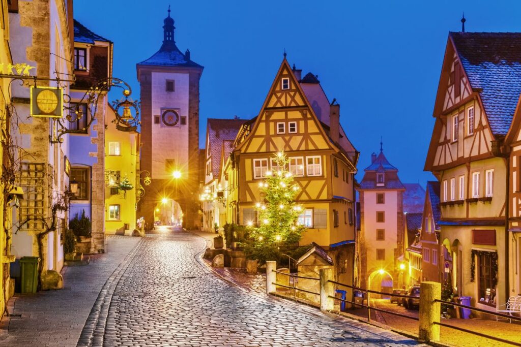 Das weltbekannte Plönlein in Rothenburg ob der Tauber mit Weihnachtsbaum und festlicher Beleuchtung zur Dämmerung.