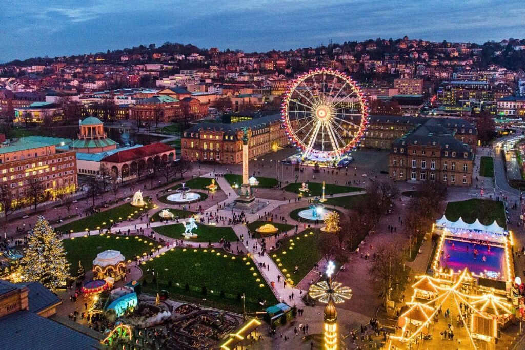 Stuttgarter Schlossplatz im Winter mit festlich beleuchtetem Weihnachtsmarkt, Riesenrad und Lichterinstallationen