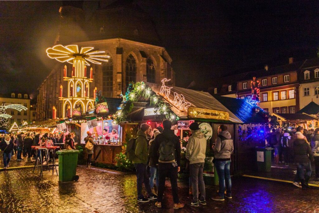 Weihnachtsmarkt in Heidelberg mit Weihnachtspyramide und Blick auf die Heiliggeistkirche