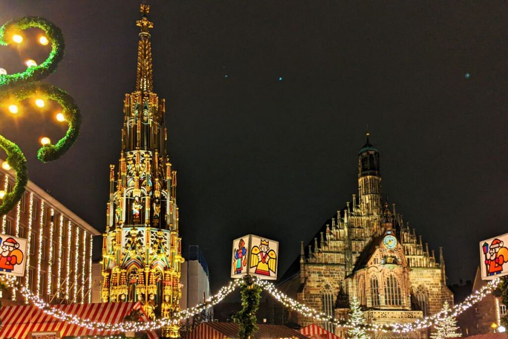 Der Nürnberger Christkindlesmarkt mit rot-weißen Stoffdächern vor der Frauenkirche zur blauen Stunde.