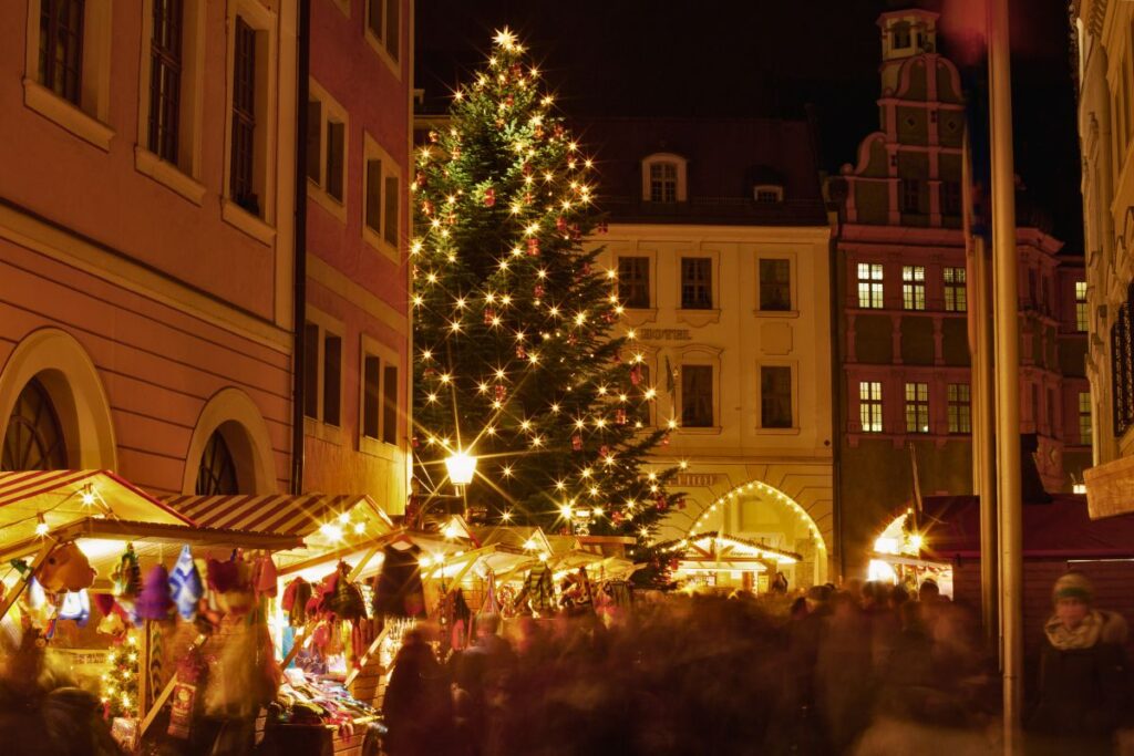 Dichtes Gedränge und stimmungsvolle Beleuchtung auf dem Schlesischen Christkindelmarkt in Görlitz mit großem Weihnachtsbaum.