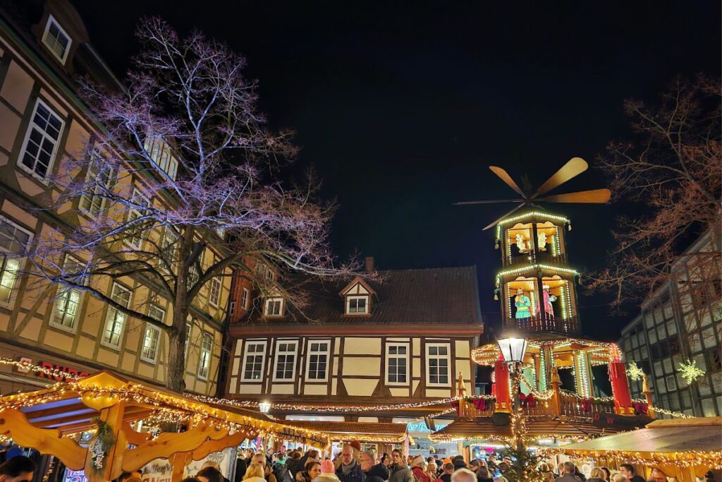 Große, beleuchtete Weihnachtspyramide auf dem Celler Weihnachtsmarkt, umgeben von historischen Fachwerkhäusern bei Nacht.