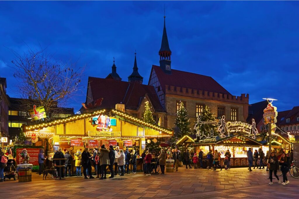 Der beleuchtete Göttinger Weihnachtsmarkt vor dem Alten Rathaus und der Johanniskirche zur blauen Stunde.