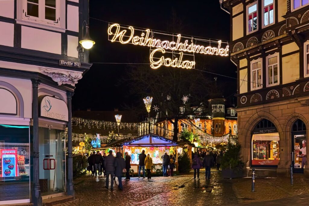 Eingangsbereich zum Weihnachtsmarkt in der Altstadt von Goslar mit großem Leuchtschriftzug über der Kopfsteinpflaster-Gasse.