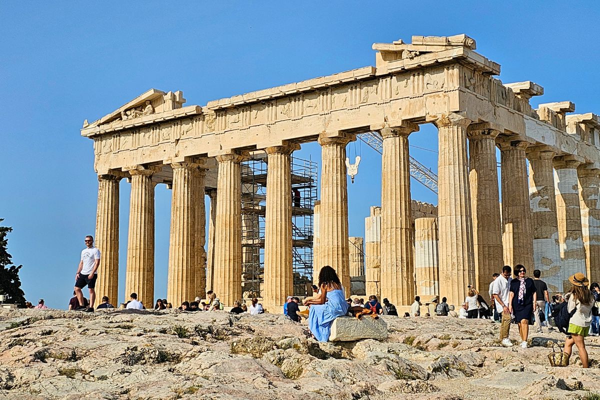 Der Parthenon-Tempel auf der Akropolis in Athen unter strahlend blauem Himmel mit Besuchern im Vordergrund.
