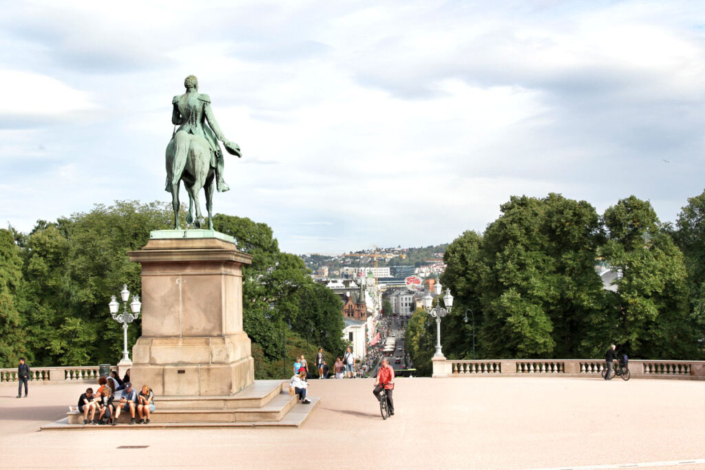 Rückenansicht der Reiterstatue von König Karl Johan vor dem Schloss mit Panoramablick über die Karl Johans gate und die Osloer Innenstadt