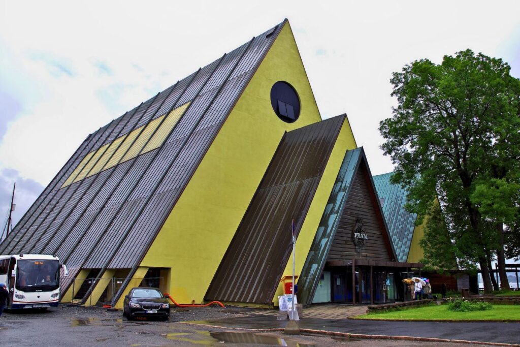 Die markante dreieckige Architektur des Fram Museums auf Bygdøy mit gelber und brauner Fassade unter bewölktem Himmel