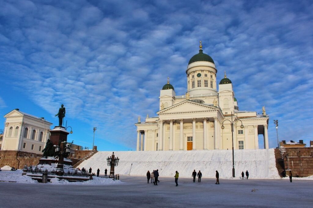 Der weiße Dom von Helsinki, der über dem verschneiten Senatsplatz thront, unter blauem Himmel.