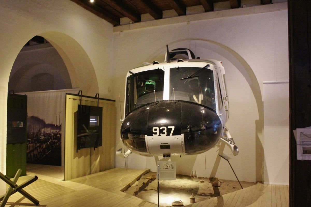 Weißes Hubschrauber-Cockpit (Bell UH-1), das als Exponat in der Ausstellungshalle hängt