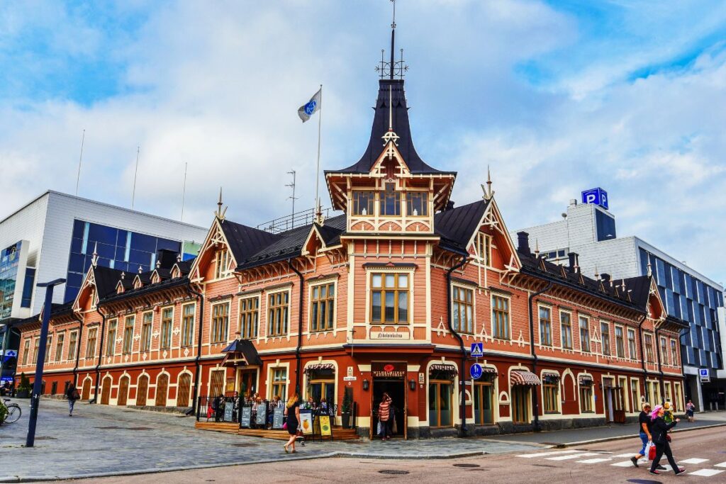 Das historische Holzgebäude Nikolainkulma in Jyväskylä mit verzierter Fassade an einer Straßenecke.