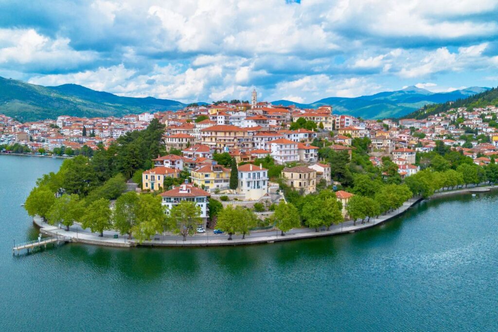 Luftaufnahme der Stadt Kastoria in Nordgriechenland, die auf einer Halbinsel im tiefblauen Lake Orestiada liegt, umgeben von grünen Bergen.