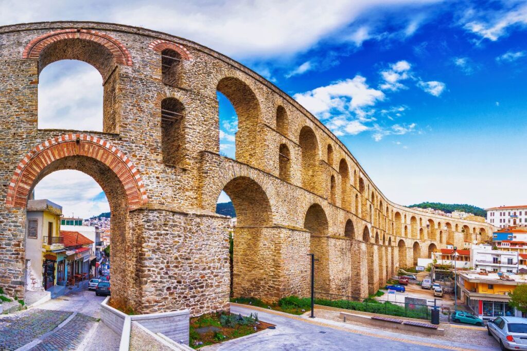 Das massive, historische Kamares-Aquädukt in Kavala mit seinen großen Steinbögen, die sich über die Häuser und Gassen der Stadt spannen.