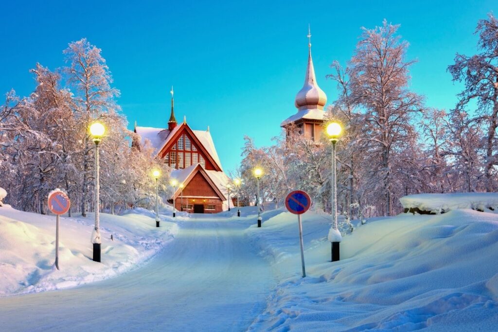 Die einzigartige rote Holzkirche von Kiruna in einer tief verschneiten Winterlandschaft in Schwedisch-Lappland.
