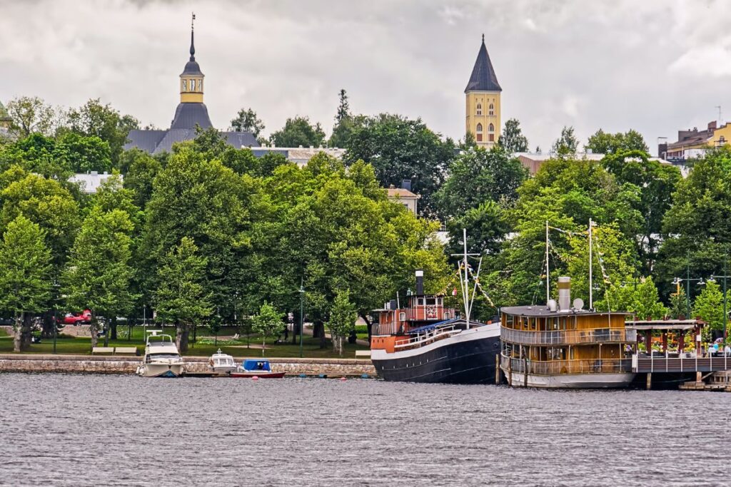 Der Hafen von Lappeenranta am Saimaa-See mit historischen Dampfschiffen und grünen Bäumen im Hintergrund.