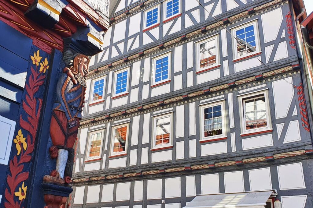 Nahaufnahme einer farbenprächtig verzierten Fachwerksäule mit einer geschnitzten Figur an einem historischen Haus in der Melsunger Altstadt.