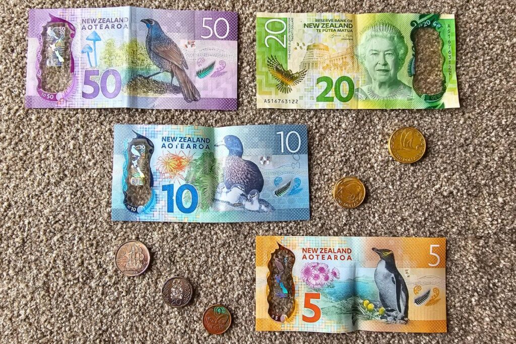 Neuseeländische Dollarnoten (5, 10, 20, 50) und Münzen mit Abbildungen von einheimischen Vögeln und Königin Elisabeth II.