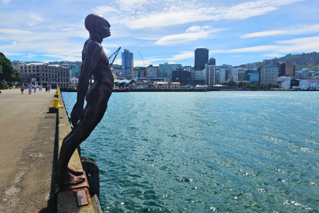 Die Skulptur „Solace in the Wind“ an der Waterfront von Wellington mit der Skyline im Hintergrund.