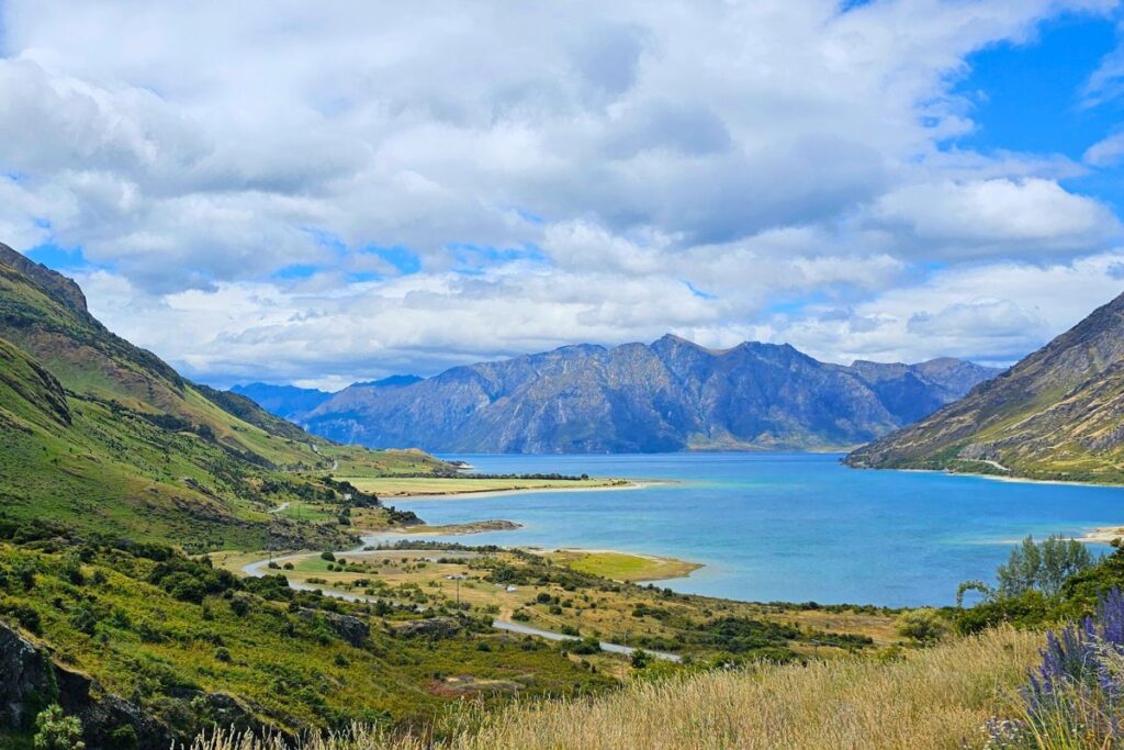 Tiefblauer Lake Hāwea in Neuseeland, von der Panoramastraße aus gesehen, eingerahmt von steilen Bergen.