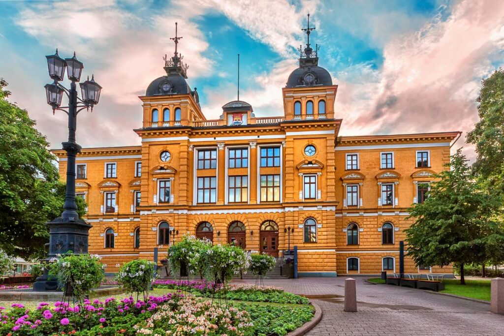 Das imposante gelbe Rathaus von Oulu im Neorenaissance-Stil unter einem dramatischen Abendhimmel.
