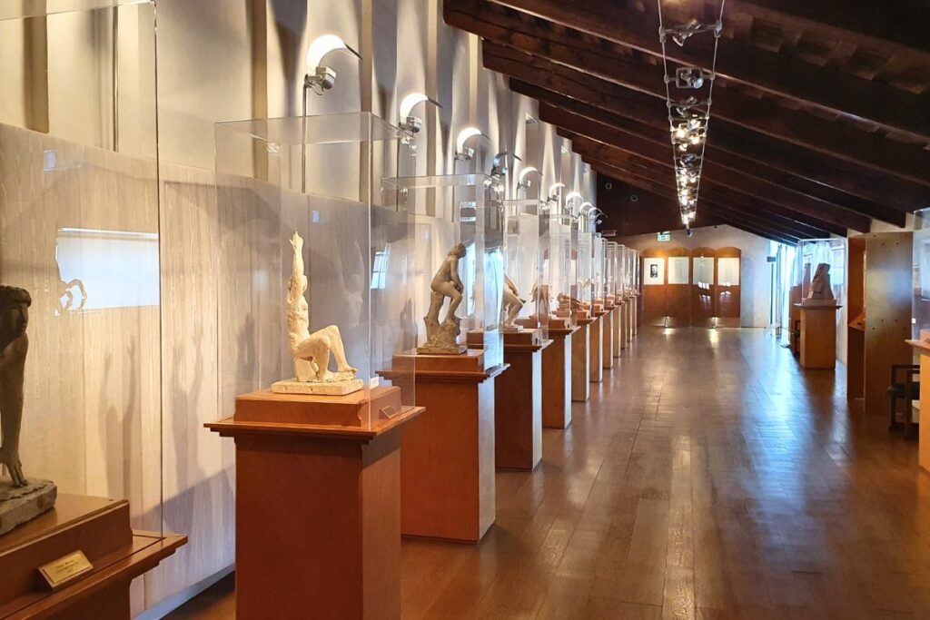 Moderne Ausstellung im Dachgeschoss des Palazzo Thiene mit zahlreichen weißen Skulpturen in Glaskästen unter einer rustikalen Holzbalkendecke.