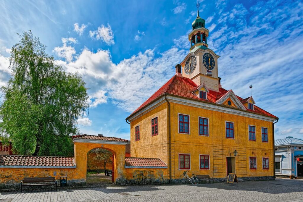 Das historische gelbe Rathaus in der Altstadt von Rauma mit Uhrturm und Kopfsteinpflaster.