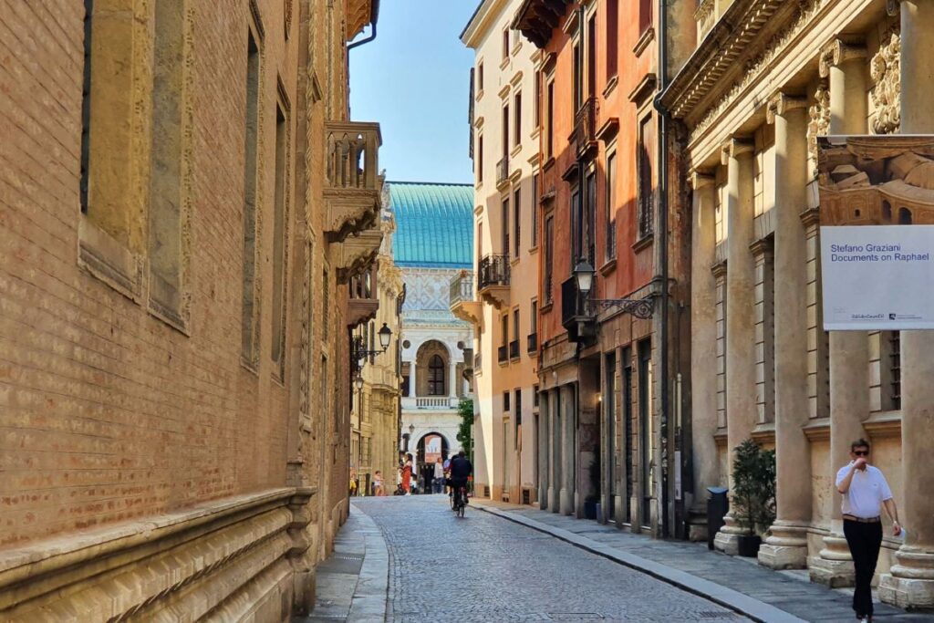 Blick in die elegante Gasse Via Contrà Porti in Vicenza, gesäumt von hohen Adelspalästen im Renaissance- und Gotik-Stil unter blauem Himmel.