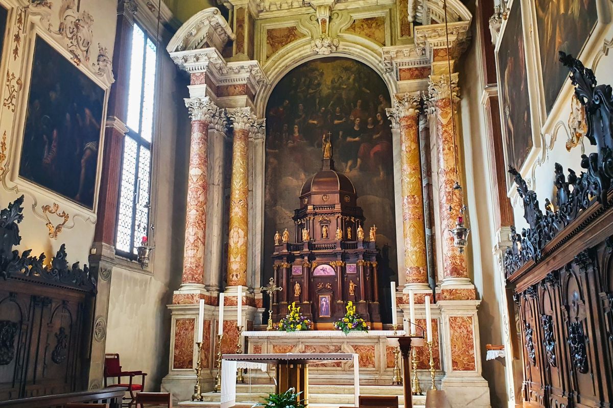 Detailansicht einer prunkvollen Seitenkapelle im Dom von Vicenza mit einem dunklen Holztabernakel, flankiert von marmorierten Säulen und einem großen religiösen Gemälde im Hintergrund.