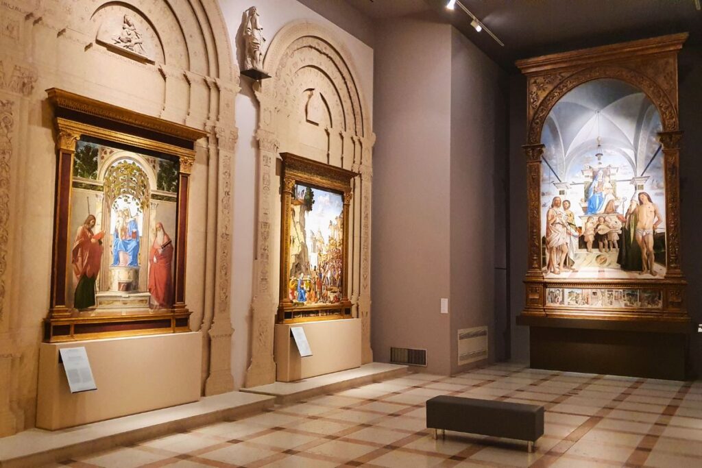 Blick in einen hohen Ausstellungssaal im Palazzo Chiericati mit großen religiösen Altarbildern und kunstvollen Renaissance-Gemälden an den Wänden.