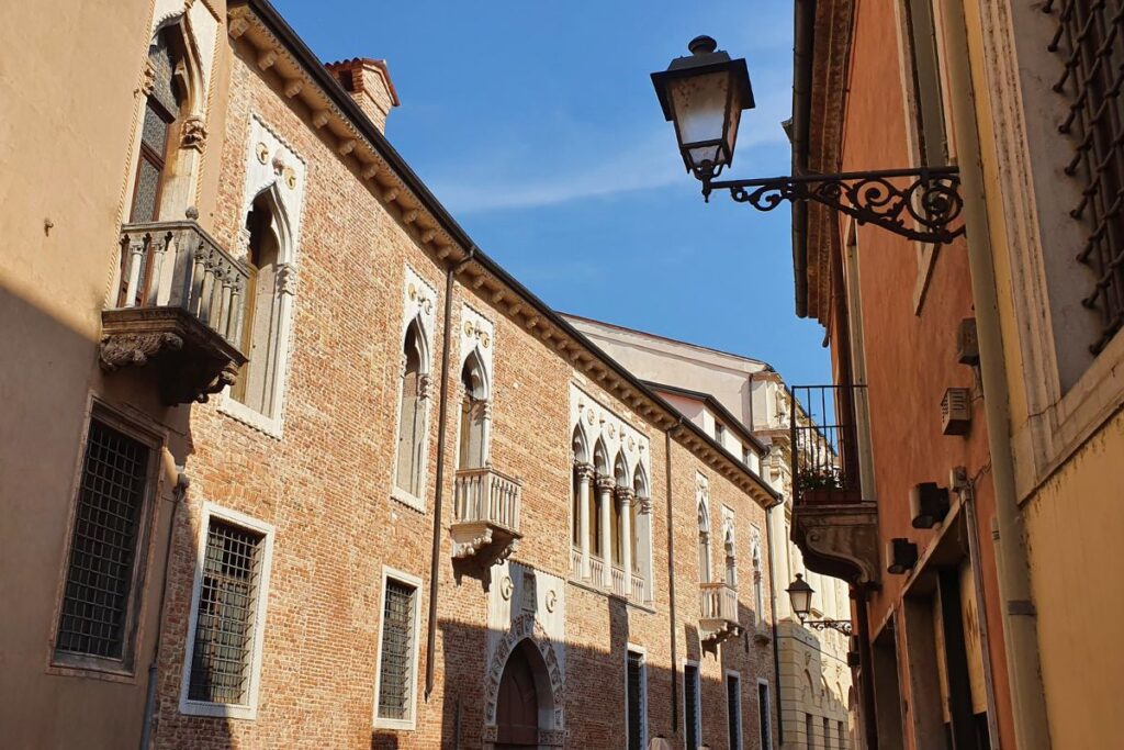 Die Backsteinfassade des Palazzo Porto Colleoni im Stil der venezianischen Gotik mit verspielten weißen Fensterrahmen und Spitzbögen.