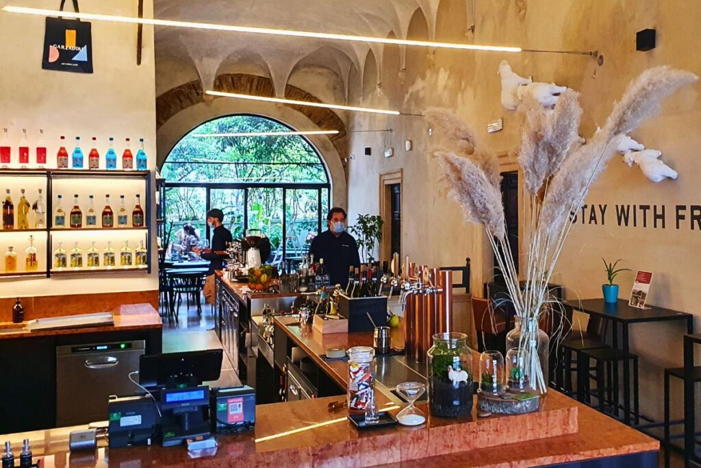 Modern gestalteter Innenraum des Restaurants Garzadori in Vicenza mit einer Bar, Pflanzen und dem Schriftzug „STAY WITH FR...“ an der Wand.