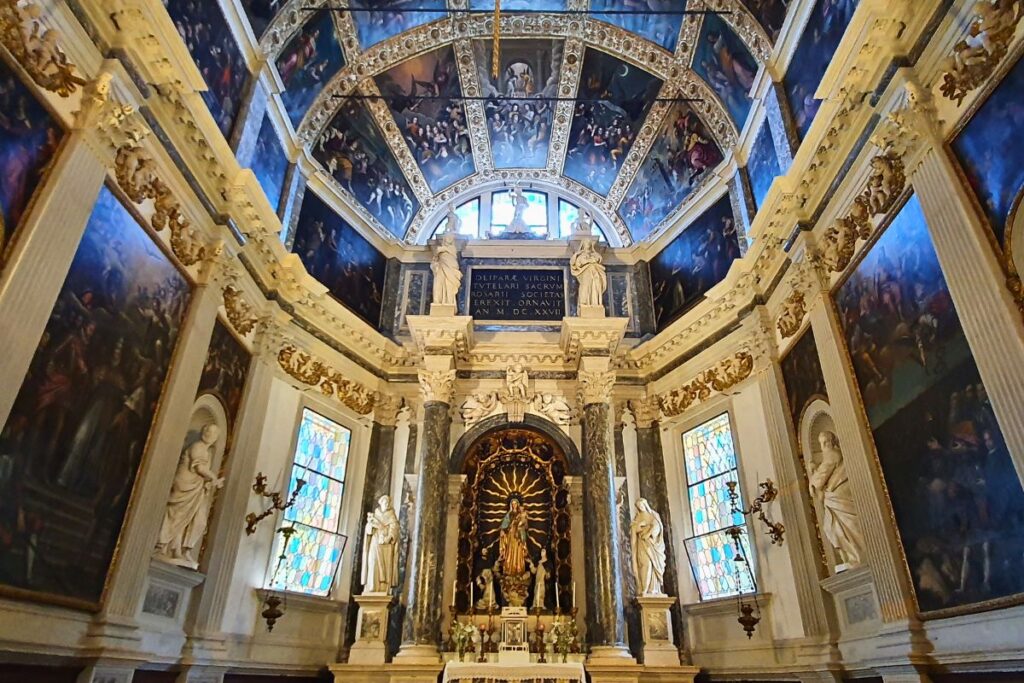 Blick in die beeindruckende Cappella della Vergine del Rosario in der Kirche Santa Corona. Der Raum ist reich geschmückt mit großen Ölgemälden an den Seitenwänden und einem Altar unter einer bemalten Gewölbedecke.